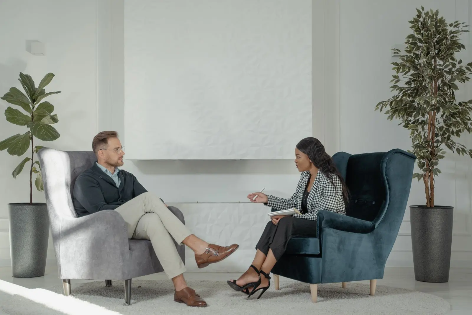 Sesión de terapia: una psicóloga conversa con su paciente sentados frente a frente en una consulta luminosa
